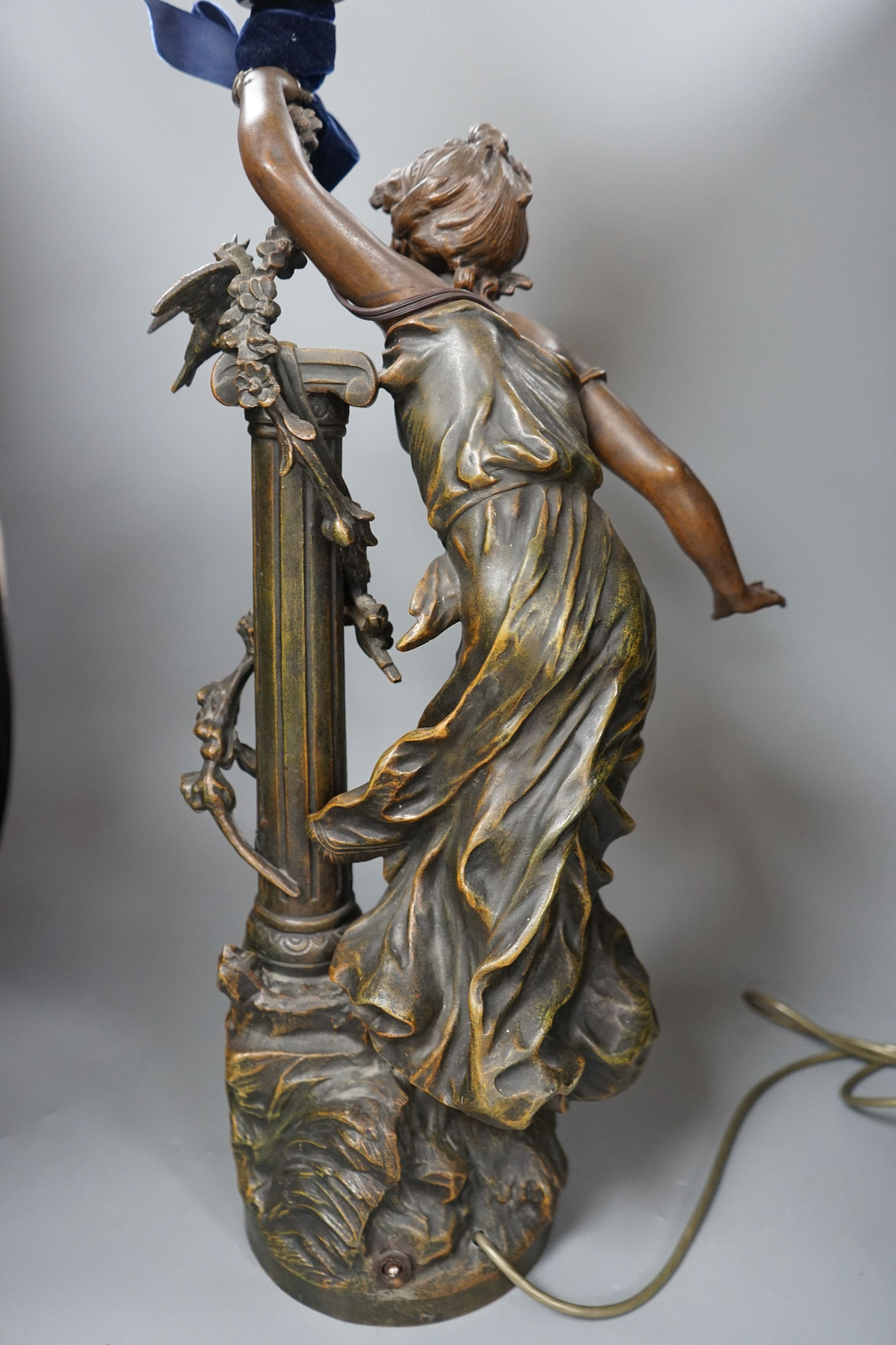 An Art Nouveau style figural lamp, with an amber glass flambe shaped shade, 77cms high including shade